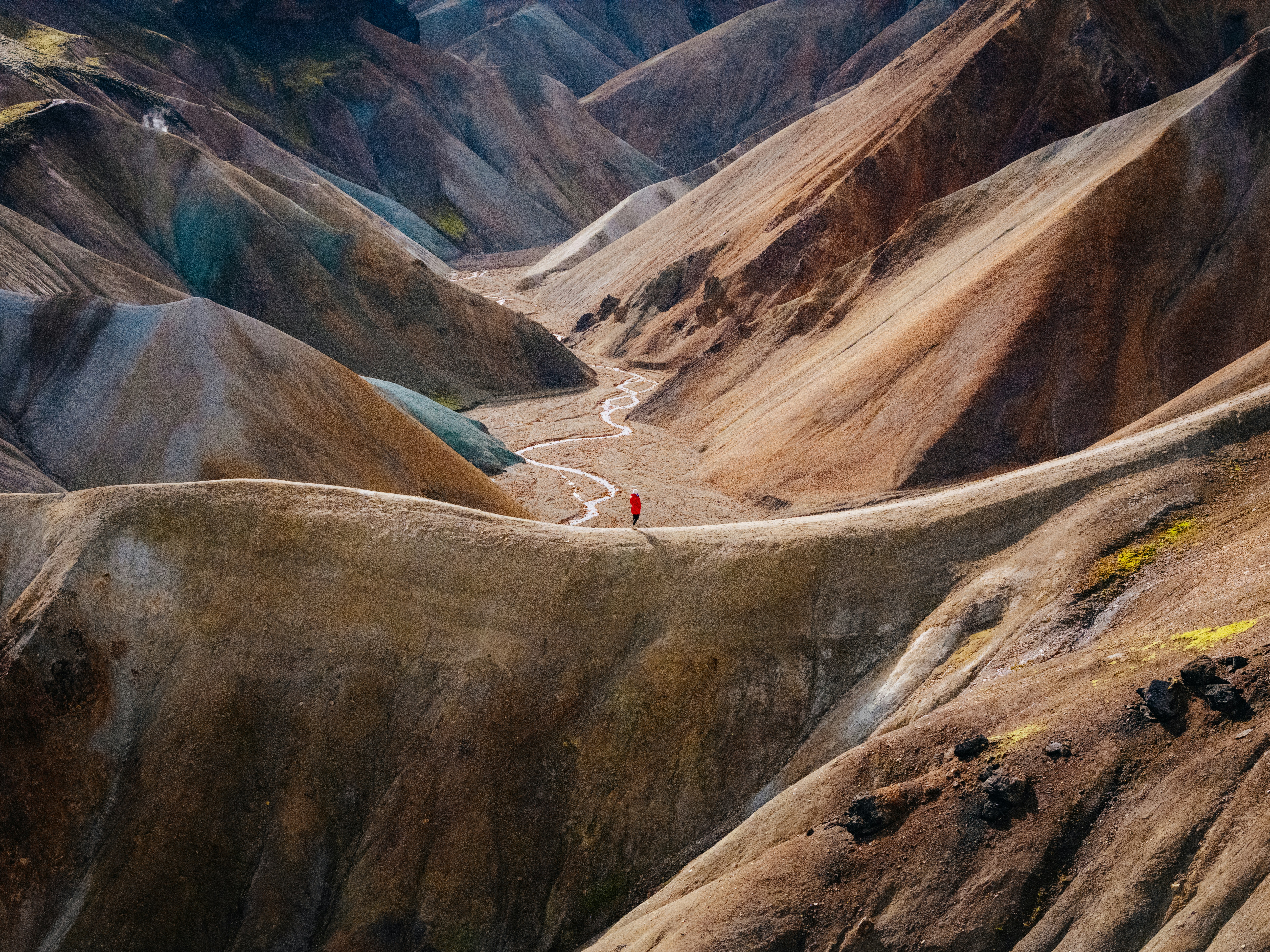 A person in a mountain landscape looking at a windy path through a valley.